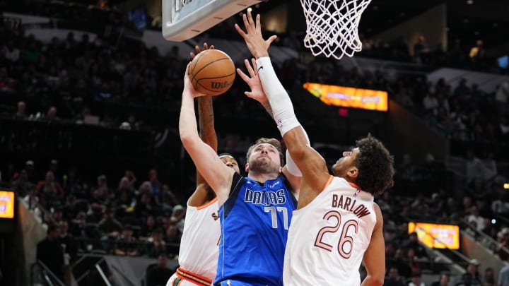 Mar 19, 2024; San Antonio, Texas, USA;  Dallas Mavericks guard Luka Doncic (77) goes up for a shot between San Antonio Spurs guard Blake Wesley (14) and forward Dominick Barlow (26) at Frost Bank Center. Mandatory Credit: Daniel Dunn-USA TODAY Sports