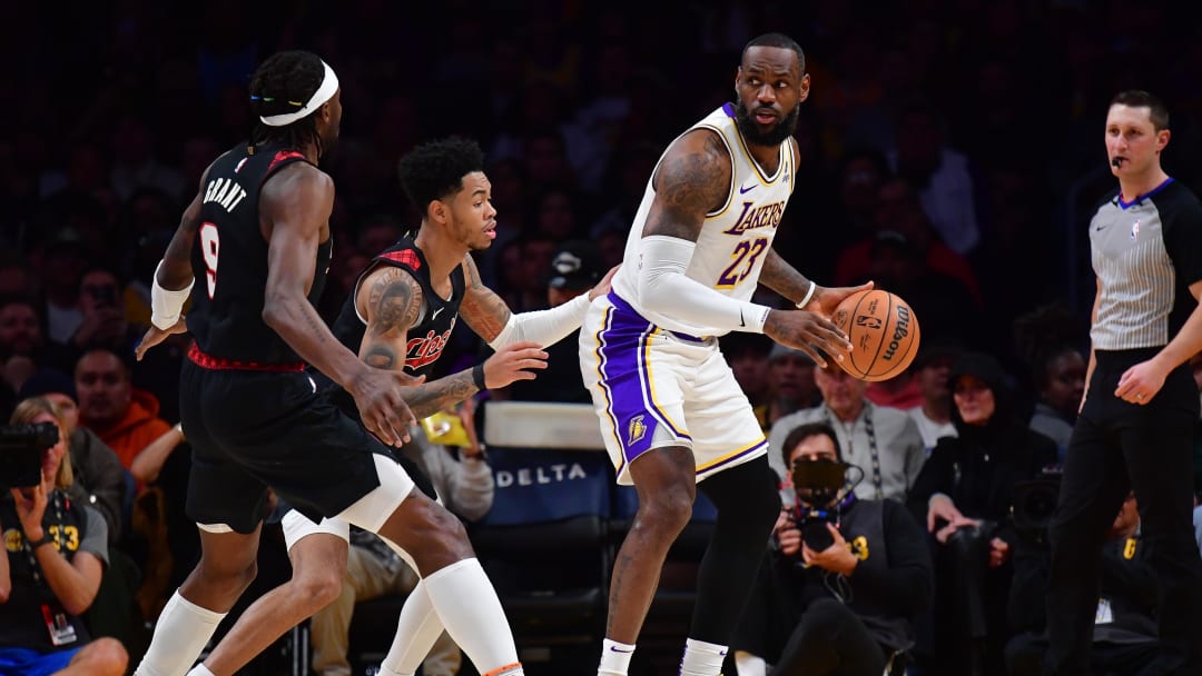 Jan 21, 2024; Los Angeles, California, USA; Los Angeles Lakers forward LeBron James (23) controls the ball against Portland Trail Blazers guard Anfernee Simons (1) and forward Jerami Grant (9) during the first half at Crypto.com Arena. Mandatory Credit: Gary A. Vasquez-USA TODAY Sports