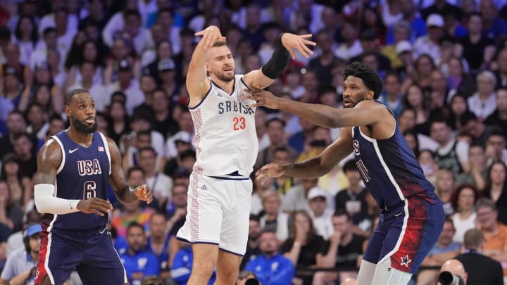 Jul 28, 2024; Villeneuve-d'Ascq, France; Serbia shooting guard Marko Guduric (23) passes against United States guard Lebron James (6) and center Joel Embiid (11) in the second quarter against Serbia during the Paris 2024 Olympic Summer Games at Stade Pierre-Mauroy. Mandatory Credit: John David Mercer-USA TODAY Sports