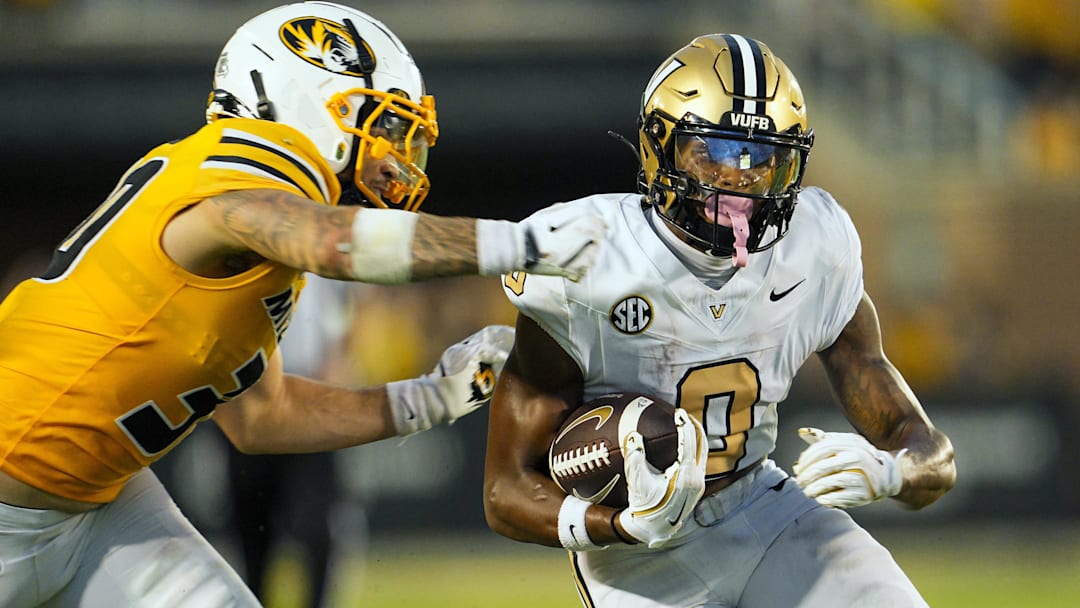 Sep 21, 2024; Columbia, Missouri, USA; Vanderbilt Commodores wide receiver Junior Sherrill (0) runs with the ball against Missouri Tigers linebacker Chuck Hicks (30) during overtime at Faurot Field at Memorial Stadium. Mandatory Credit: Jay Biggerstaff-Imagn Images