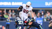 Nov 9, 2025; Seattle, Washington, USA;  Arizona Cardinals tight end Trey McBride (85) leaps over Seattle Seahawks cornerback Devon Witherspoon (21) and Seattle Seahawks safety Coby Bryant (8) during the third quarter at Lumen Field. Mandatory Credit: Steven Bisig-Imagn Images