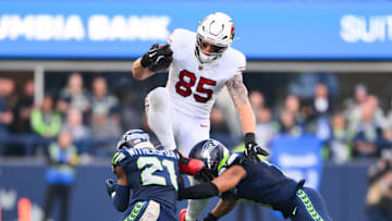Nov 9, 2025; Seattle, Washington, USA;  Arizona Cardinals tight end Trey McBride (85) leaps over Seattle Seahawks cornerback Devon Witherspoon (21) and Seattle Seahawks safety Coby Bryant (8) during the third quarter at Lumen Field. Mandatory Credit: Steven Bisig-Imagn Images