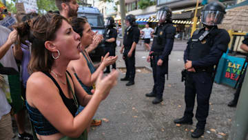 Protesters are seen shouting slogans in front of a line of...