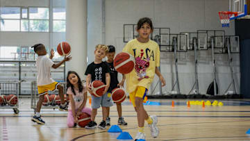 A young female hooper is seen practicing basketball while...