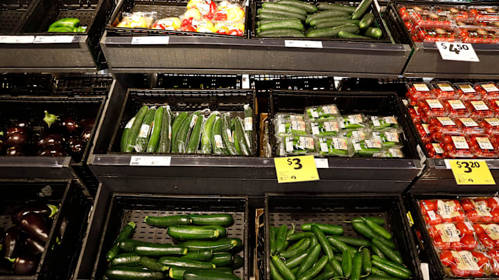 Cucumbers and tomatoes are displayed with price tags inside...