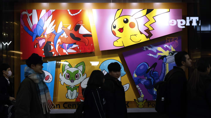 Customers walk past the Pokemon Store graffiti at Tokyo...