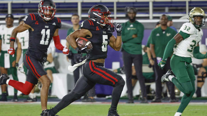 Nov 1, 2024; Boca Raton, Florida, USA; Florida Atlantic Owls running back CJ Campbell Jr. (5) runs the ball getting past South Florida Bulls defensive back James Chenault (32) as Owls wide receiver Marlyn Johnson (11) follows along during the second half at FAU Stadium. Mandatory Credit: Reinhold Matay-Imagn Images Nov 1, 2024; Boca Raton, Florida, USA; Florida Atlantic Owls running back CJ Campbell Jr. (5) runs the ball getting past South Florida Bulls defensive back James Chenault (32) as Owls wide receiver Marlyn Johnson (11) follows along during the second half at FAU Stadium. Mandatory Credit: Reinhold Matay-Imagn Images