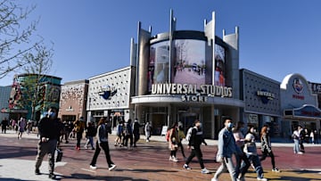 Tourists wearing face masks walk past the Universal Studios...