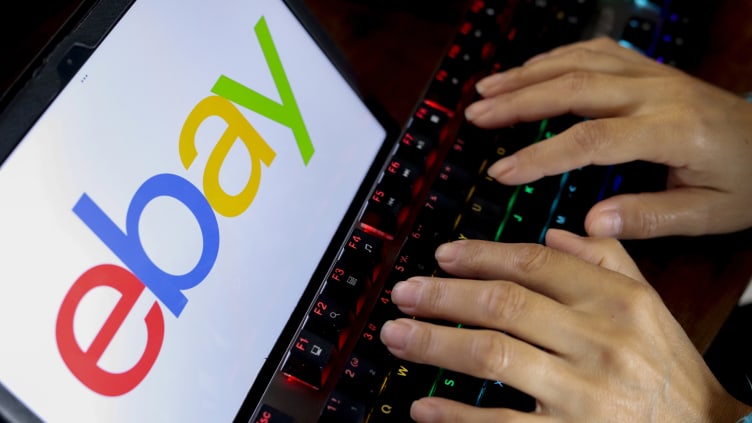 In this photo illustration, a person types next to the eBay...