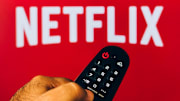 In this photo illustration, a hand holding a TV remote...