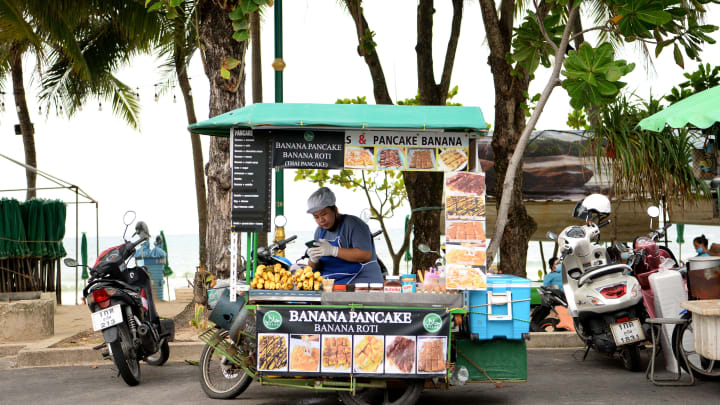 A bananna pancake vendor sits on her vehicle.
Thailands...