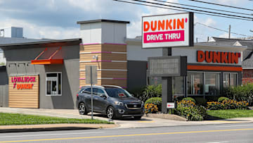 A car exits a Dunkin' drive thru. Dunkin' is the largest...