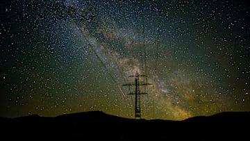 A electrical powerline in front of the Milky Way stars at...