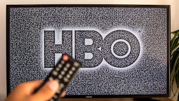 In this photo illustration a close-up of a hand holding a TV...