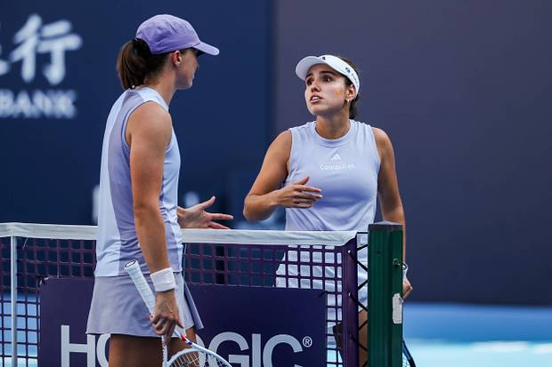 Iga Swiatek talks with Camila Osorio at the net after a match.