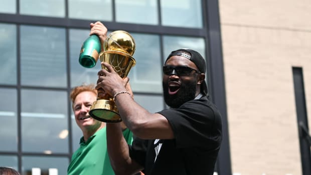 Jaylen Brown lifts the 2024 NBA Finals MVP Award while on a duck boat during the Boston Celtics championship parade.