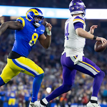 Jan 13, 2025; Glendale, AZ, USA; Minnesota Vikings quarterback Sam Darnold (14) is pursued by Los Angeles Rams linebacker Jared Verse (8) during an NFC wild card game at State Farm Stadium. Mandatory Credit: Mark J. Rebilas-Imagn Images