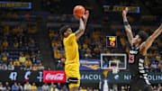 Feb 19, 2025; Morgantown, West Virginia, USA; West Virginia Mountaineers guard Jonathan Powell (11) shoots a three point shot over Cincinnati Bearcats forward Dillon Mitchell (23) during the second half at WVU Coliseum. Mandatory Credit: Ben Queen-Imagn Images