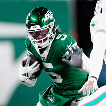 New York Jets wide receiver Garrett Wilson (5) runs with the ball as he tries to find a way past Miami Dolphins cornerback Jalen Ramsey (5), Sunday January 5, 2025, in East Rutherford.