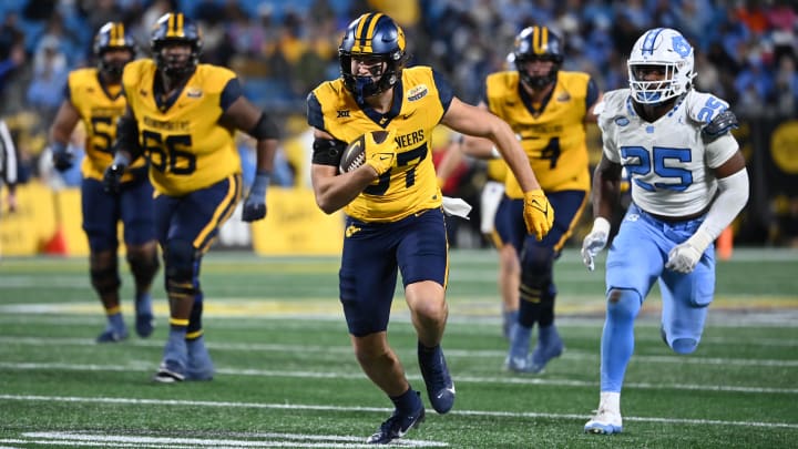 Dec 27, 2023; Charlotte, NC, USA; West Virginia Mountaineers tight end Kole Taylor (87) with the ball as North Carolina Tar Heels linebacker Kaimon Rucker (25) defends in the fourth quarter at Bank of America Stadium.