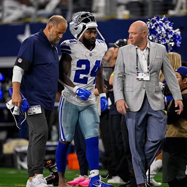 Dallas Cowboys running back Miles Sanders walks off the field with team staff during a game against the Green Bay Packers