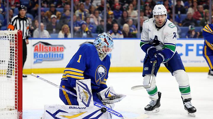 Jan 6, 2026; Buffalo, New York, USA;  Vancouver Canucks left wing Jake Debrusk (74) tries to deflect a shot on Buffalo Sabres goaltender Ukko-Pekka Luukkonen (1) during the first period at KeyBank Center. Mandatory Credit: Timothy T. Ludwig-Imagn Images