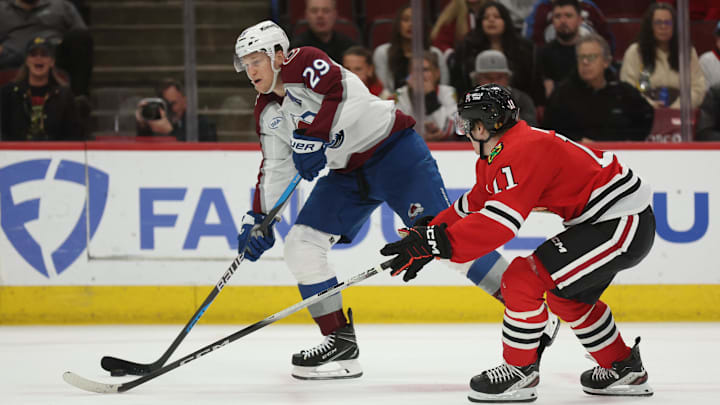 Apr 2, 2025; Chicago, Illinois, USA; Colorado Avalanche center Nathan MacKinnon (29) and Chicago Blackhawks center Oliver Moore (11) battle for control of the puck during the third period at United Center. Mandatory Credit: Talia Sprague-Imagn Images