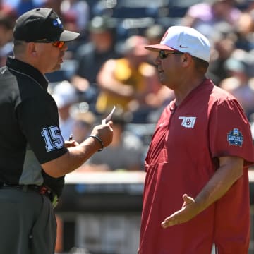 Jun 22, 2022; Omaha, NE, USA; Oklahoma Sooners head coach Skip Johnson discusses a call with an umpire during the game against the Texas A&M Aggies at Charles Schwab Field. Mandatory Credit: Steven Branscombe-USA TODAY Sports
