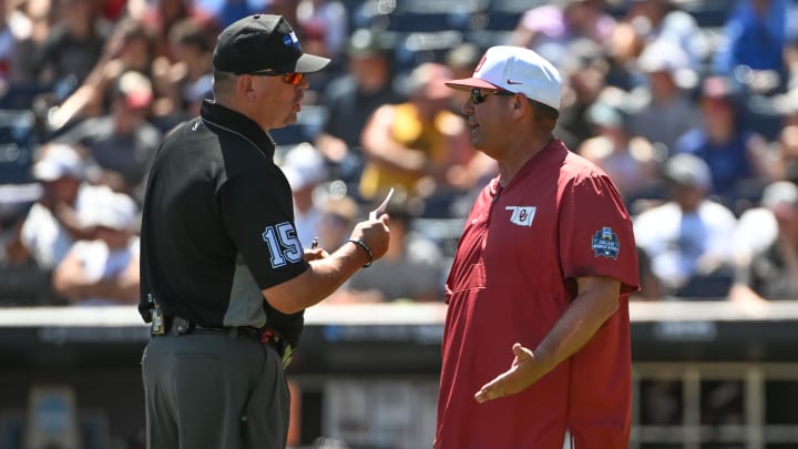 Jun 22, 2022; Omaha, NE, USA; Oklahoma Sooners head coach Skip Johnson discusses a call with an umpire during the game against the Texas A&M Aggies at Charles Schwab Field. Mandatory Credit: Steven Branscombe-USA TODAY Sports