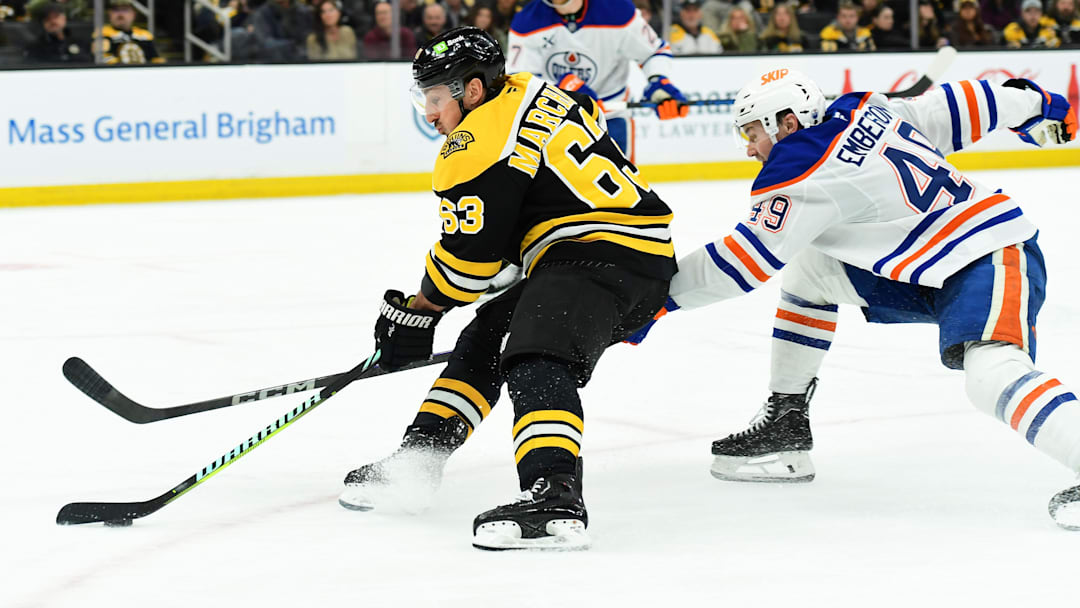 Jan 7, 2025; Boston, Massachusetts, USA;  Boston Bruins left wing Brad Marchand (63) skates with the puck while Edmonton Oilers defenseman Ty Emberson (49) defends during the third period at TD Garden. Mandatory Credit: Bob DeChiara-Imagn Images