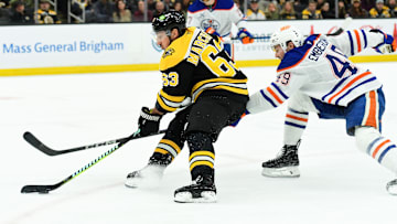 Jan 7, 2025; Boston, Massachusetts, USA;  Boston Bruins left wing Brad Marchand (63) skates with the puck while Edmonton Oilers defenseman Ty Emberson (49) defends during the third period at TD Garden. Mandatory Credit: Bob DeChiara-Imagn Images