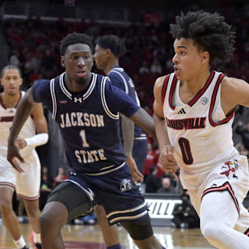 Nov 6, 2025; Louisville, Kentucky, USA;  Louisville Cardinals guard Mikel Brown Jr. (0) drives to the basket against Jackson State Tigers guard Dorian McMillian (1) during the second half at KFC Yum! Center. Louisville defeated Jackson State 106-70. Mandatory Credit: Jamie Rhodes-Imagn Images