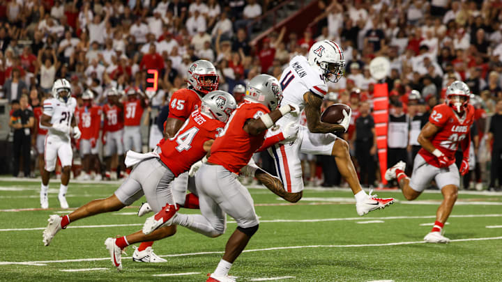 Aug 31, 2024; Tucson, Arizona, USA; Arizona Wildcats wide receiver Tetairoa McMillan (4) dodges tackle from New Mexico Lobos safety Christian Ellis (8) and New Mexico Lobos safety Noa Pola-Gates (34) during third quarter at Arizona Stadium.