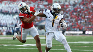 WVU football running back Jahiem White stiff arms a would-be tackler against Arizona during the 2024 football season.