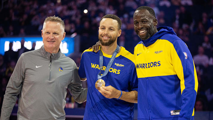 Oct 11, 2024; San Francisco, California, USA; Golden State Warriors guard Stephen Curry (center) is flanked by head coach Steve Kerr and forward Draymond Green as he is presented his gold medal for his performance for Team USA at the 2024 Summer Olympics in Paris before taking on the Sacramento Kings at Chase Center. Mandatory Credit: D. Ross Cameron-Imagn Images Oct 11, 2024; San Francisco, California, USA; Golden State Warriors guard Stephen Curry (center) is flanked by head coach Steve Kerr and forward Draymond Green as he is presented his gold medal for his performance for Team USA at the 2024 Summer Olympics in Paris before taking on the Sacramento Kings at Chase Center. Mandatory Credit: D. Ross Cameron-Imagn Images