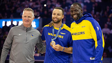 Oct 11, 2024; San Francisco, California, USA; Golden State Warriors guard Stephen Curry (center) is flanked by head coach Steve Kerr and forward Draymond Green as he is presented his gold medal for his performance for Team USA at the 2024 Summer Olympics in Paris before taking on the Sacramento Kings at Chase Center. Mandatory Credit: D. Ross Cameron-Imagn Images