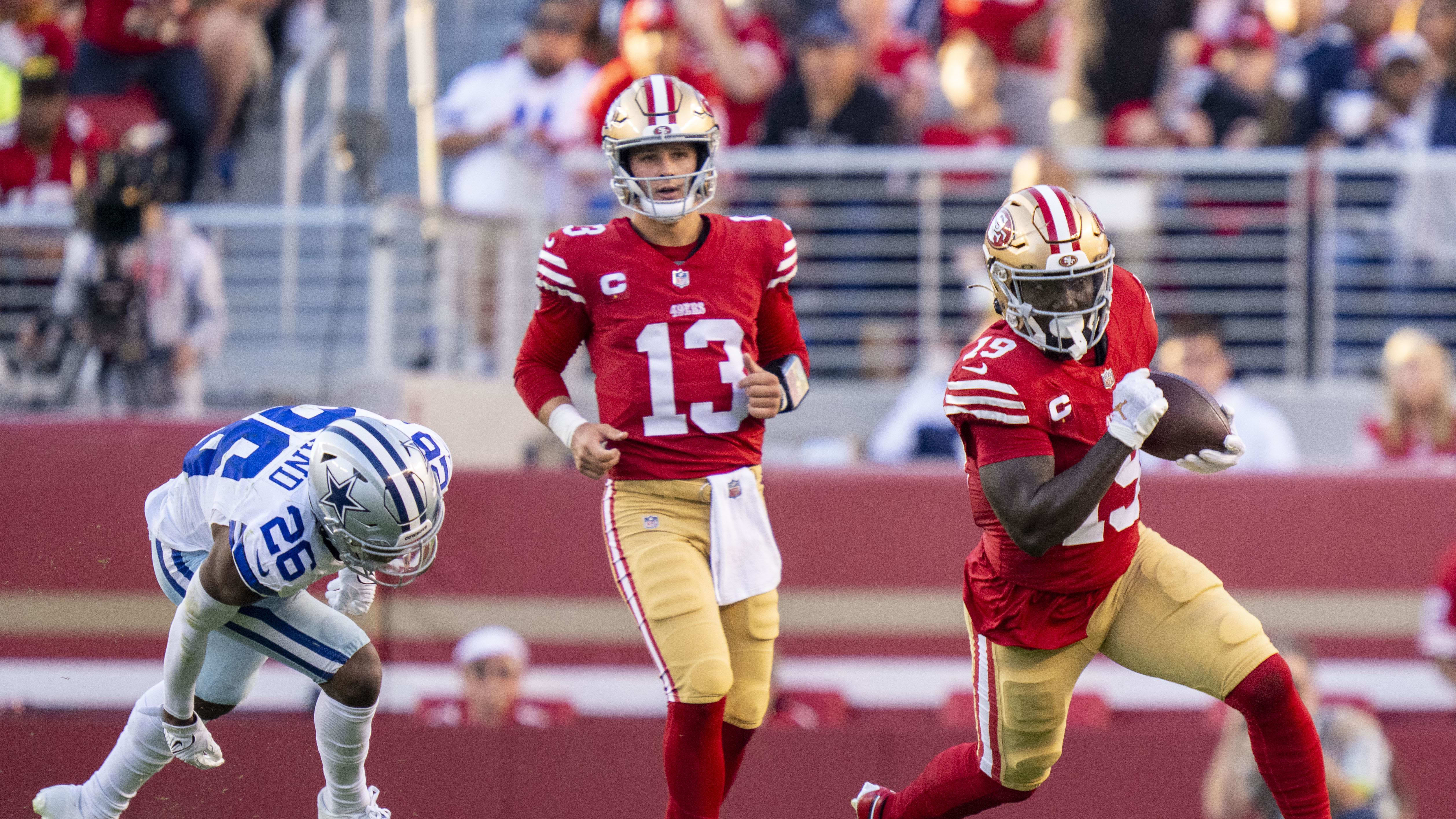 49ers quarterback Brock Purdy, left, watches in the background as wide receiver Deebo Samuel carries the ball.