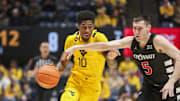 Feb 19, 2025; Morgantown, West Virginia, USA; West Virginia Mountaineers guard Sencire Harris (10) drives against Cincinnati Bearcats guard CJ Fredrick Jr. (5) during the first half at WVU Coliseum. Mandatory Credit: Ben Queen-Imagn Images
