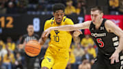 Feb 19, 2025; Morgantown, West Virginia, USA; West Virginia Mountaineers guard Sencire Harris (10) drives against Cincinnati Bearcats guard CJ Fredrick Jr. (5) during the first half at WVU Coliseum. Mandatory Credit: Ben Queen-Imagn Images