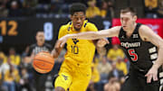 Feb 19, 2025; Morgantown, West Virginia, USA; West Virginia Mountaineers guard Sencire Harris (10) drives against Cincinnati Bearcats guard CJ Fredrick Jr. (5) during the first half at WVU Coliseum. Mandatory Credit: Ben Queen-Imagn Images