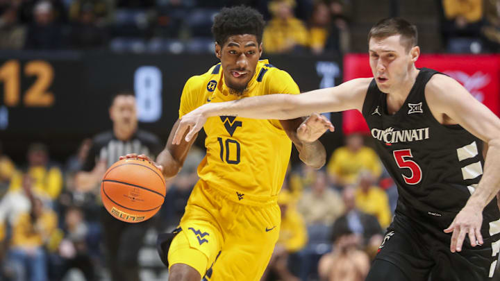 Feb 19, 2025; Morgantown, West Virginia, USA; West Virginia Mountaineers guard Sencire Harris (10) drives against Cincinnati Bearcats guard CJ Fredrick Jr. (5) during the first half at WVU Coliseum. Mandatory Credit: Ben Queen-Imagn Images