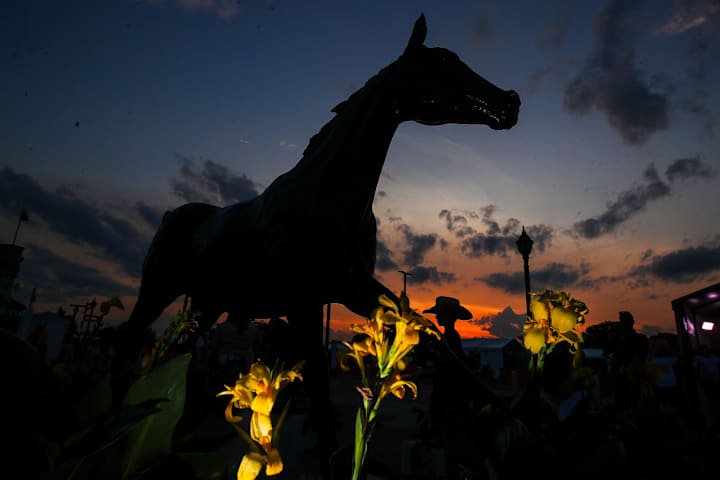 The sun sets in the background of the Barbaro statue on opening night of the spring meet at Churchill Downs.