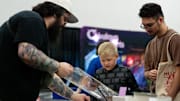 Kendall Cox, left, shows and Riece LaFavers and his son Ollie LaFavers 8 different trading cards during PopCon on Sunday, Aug. 25, 2024 in Louisville, Ky.