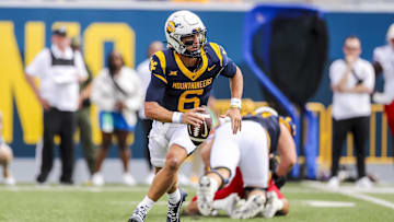 West Virginia Mountaineers quarterback Garrett Greene (6) rolls out to pass during the first quarter against the Kansas Jayhawks at Mountaineer Field at Milan Puskar Stadium.