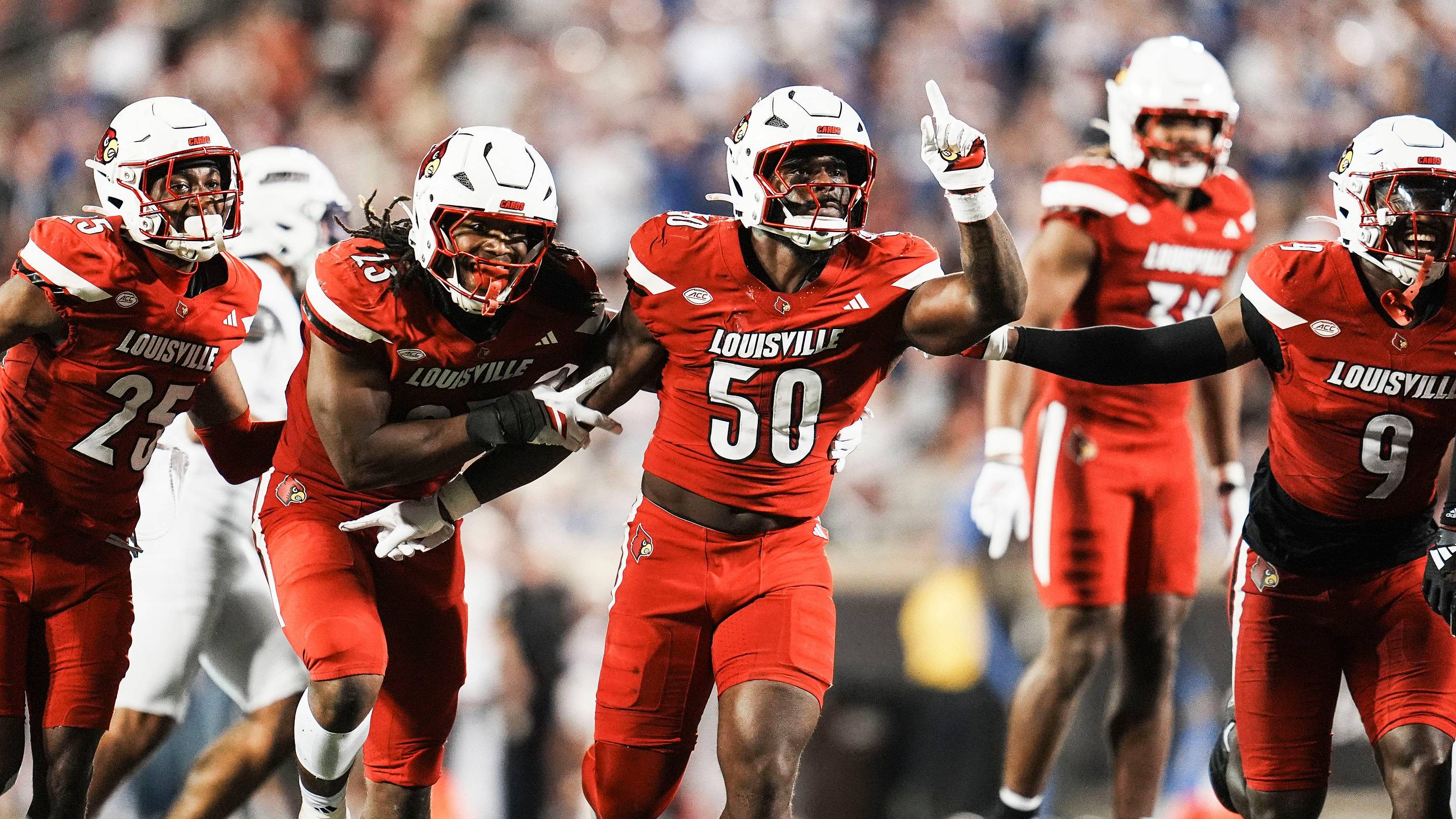 Louisville Cardinals defensive lineman Clev Lubin (50) and teammates Louisville Cardinals defensive back Tayon Holloway (25), left, and Louisville Cardinals defensive lineman Wesley Bailey (23) and Louisville Cardinals linebacker Antonio Watts (9) celebrate creating a turnover on James Madison University as the Cards' beat the visiting Dukes 28-14 Friday September 5, 2025 at L&N Credit Union Stadium in Louisville, Kentucky.