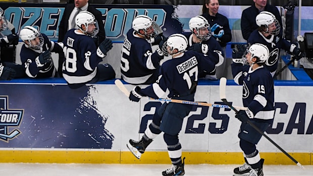 Hockey players in blue uniforms celebrate a goal score