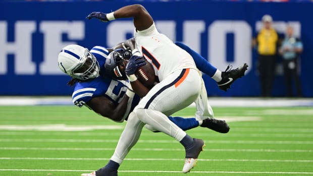 Colts linebacker Segun Olubi (blue jersey and socks; white helmet) makes a tackle of Broncos running back Audric Estime.