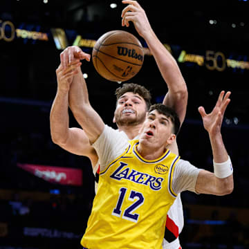 Oct 27, 2025; Los Angeles, California, USA; Los Angeles Lakers forward Jake LaRavia (12) and Portland Trail Blazers center Donovan Clingan (23) vie for the ball during the first half at Crypto.com Arena. Mandatory Credit: William Liang-Imagn Images