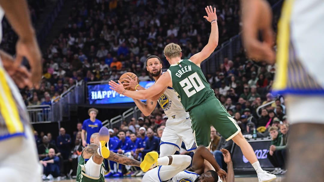 Oct 30, 2025; Milwaukee, Wisconsin, USA; Golden State Warriors guard Stephen Curry (30) looks to pass the ball after Milwaukee Bucks forward Kyle Kuzma (18) fouls forward Draymond Green (23) in the first quarter at Fiserv Forum. Mandatory Credit: Benny Sieu-Imagn Images