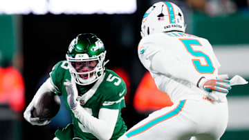 New York Jets wide receiver Garrett Wilson (5) runs with the ball as he tries to find a way past Miami Dolphins cornerback Jalen Ramsey (5), Sunday January 5, 2025, in East Rutherford.